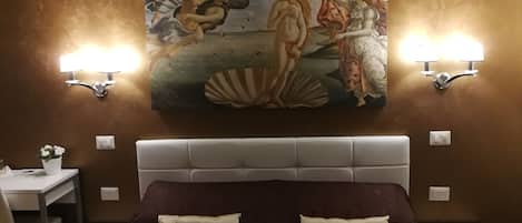 A bedroom with a large bed, two bedside tables, a desk with a chair, and a painting on the wall.
