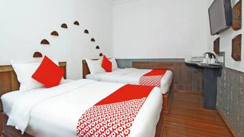 A hotel room with two beds, a TV, a small table, and a wooden floor.