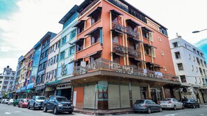 Un hotel de varios pisos con balcones, una entrada en la planta baja y coches aparcados.