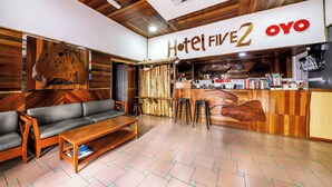 Un hall de hotel con un mostrador de recepción de madera, un sofá y una mesita de centro.
