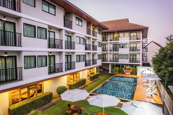 Ein mehrstöckiges Hotel mit Schwimmbad, Außenbereich und gut beleuchteten Balkonen.