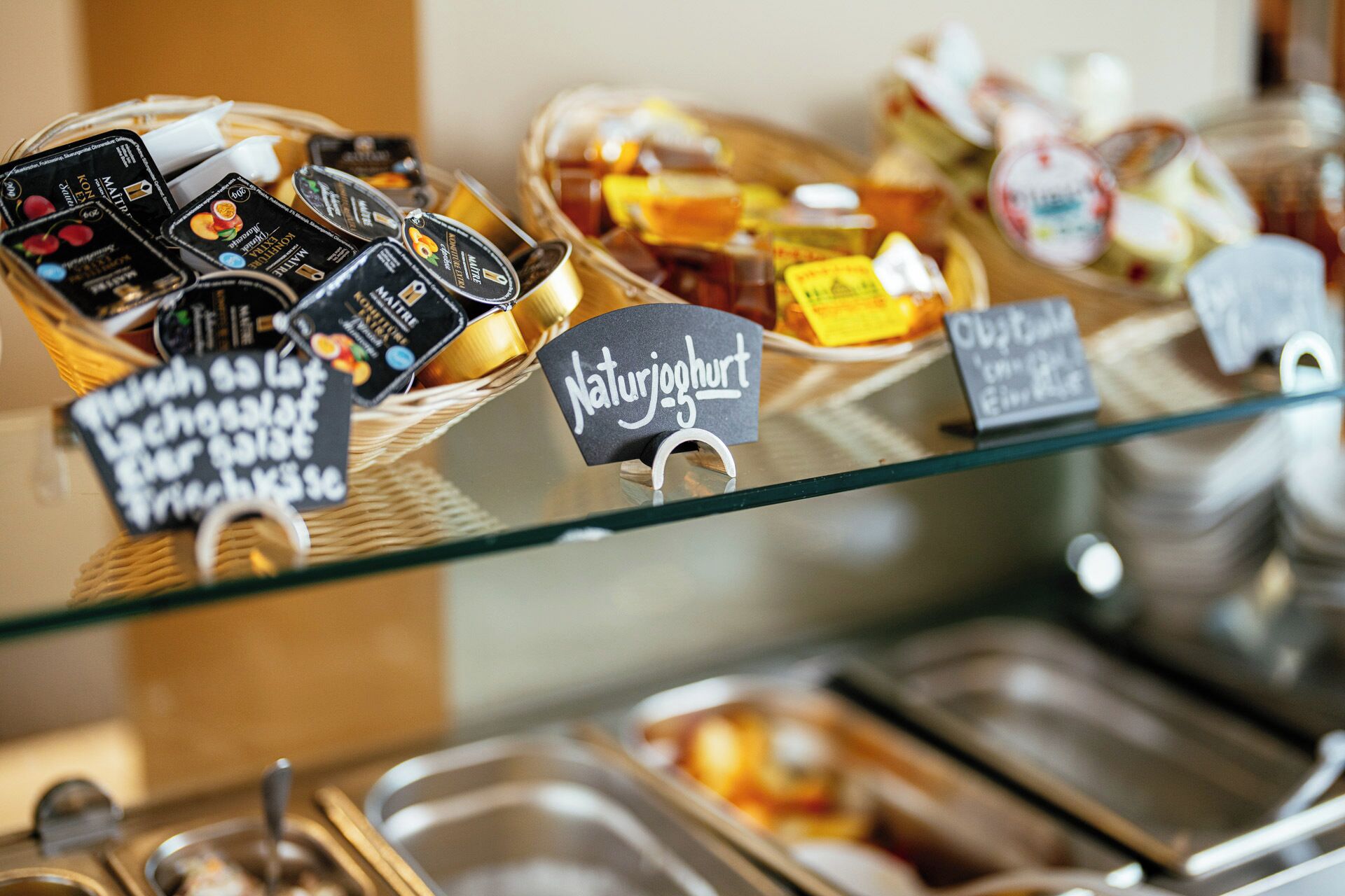 A buffet with various food items and condiments, including jars of honey and jars of preserves.