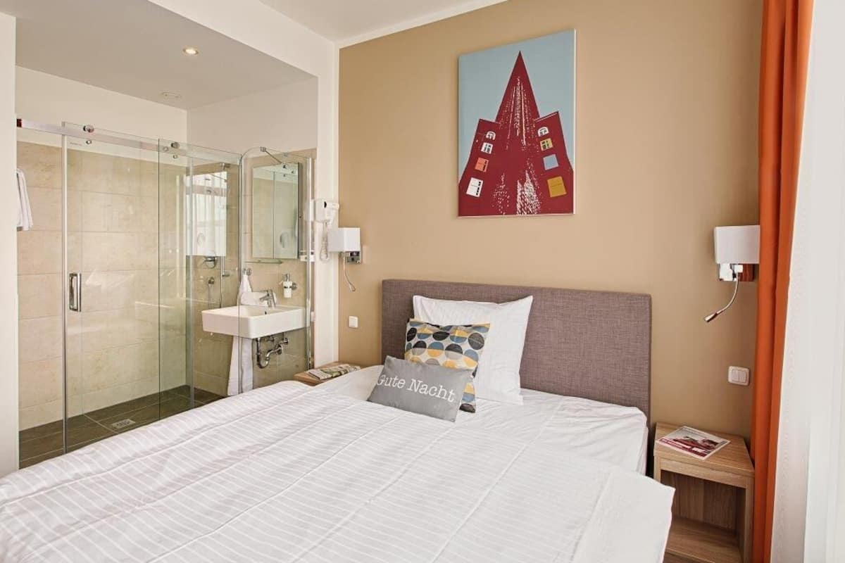A hotel room with a bed, a shower, and a bathroom.