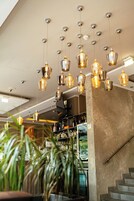 Ein modernes Interieur mit mehreren hängenden Pendelleuchten, einer Treppe und einer Bar mit Regalen voller Flaschen.
