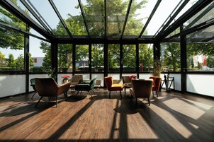 Ein modernes Interieur mit Glasdecke, Holzboden und vielfältigen Sitzgelegenheiten.