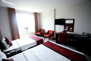 A hotel room with two beds, a desk, a chair, a TV, and a window with curtains. - Huong Son Hotel (Da Nang)