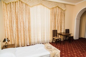 A hotel room with a bed, a table with two chairs, and curtains. - Art Hotel (Tashkent)