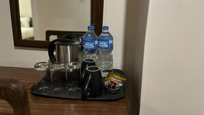 A table with a water bottle, a thermos, a kettle, and a tray with cups and a packet of snacks. - Mala Suites Thamel (Kathmandu)