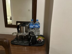 A table with a water bottle, a thermos, a kettle, and a tray with cups and a packet of snacks. - Mala Suites Thamel (Kathmandu)