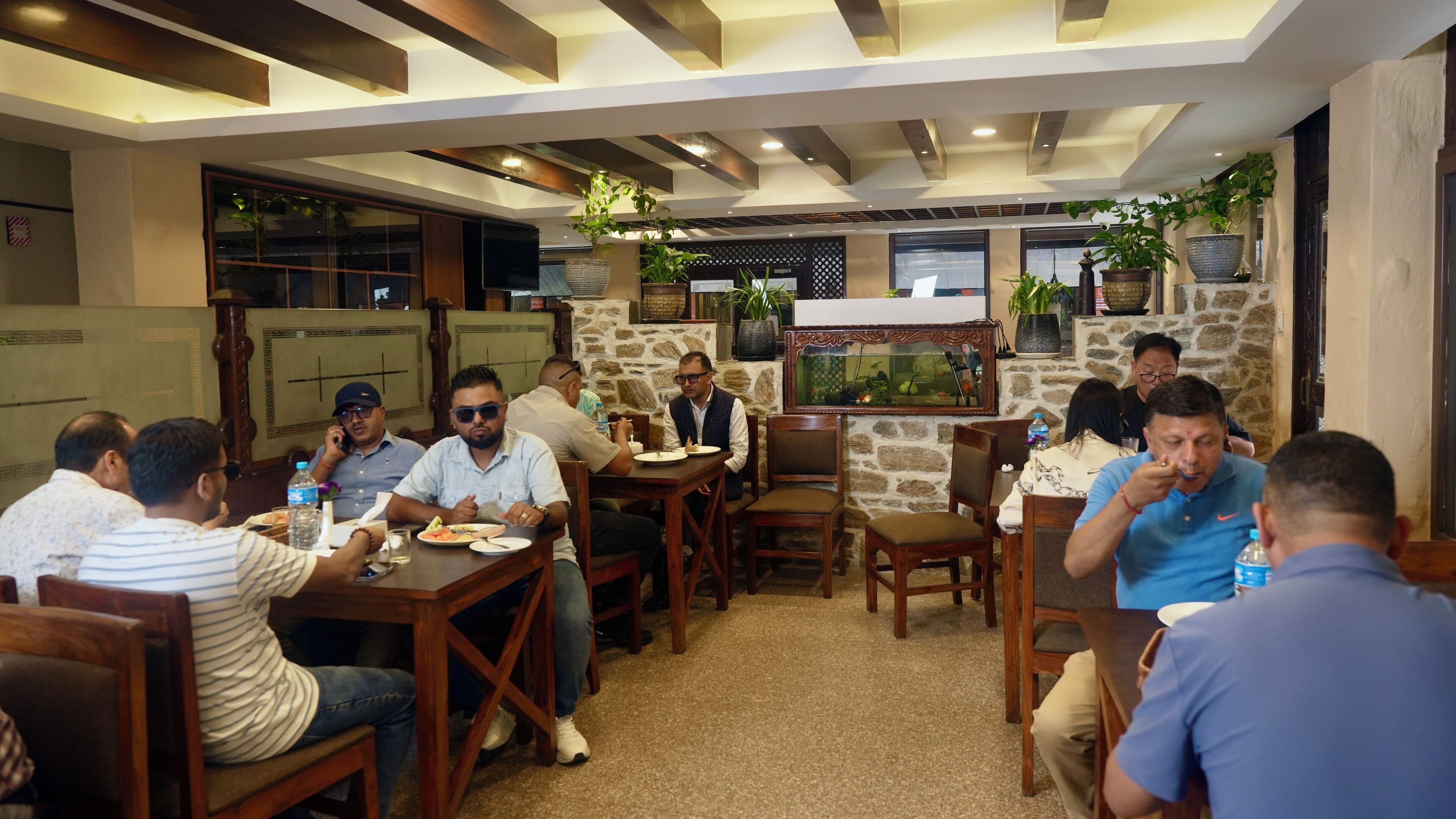 A group of people dining in a restaurant with wooden furniture and stone walls.