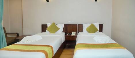 Habitación de hotel con dos camas, una mesita de noche con teléfono y dos lámparas de pared.