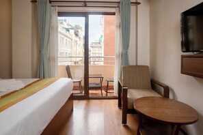 A hotel room with a bed, a chair, a small table, and a balcony with curtains. - Mala Suites Thamel (Kathmandu)