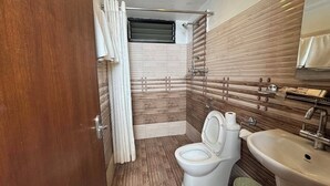 A compact bathroom with a toilet, sink, and shower area. - Mala Suites Thamel (Kathmandu)
