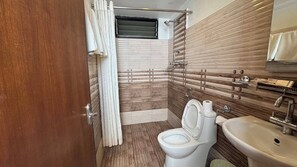 A compact bathroom with a toilet, sink, and shower area. - Mala Suites Thamel (Kathmandu)