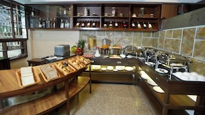 A breakfast buffet setup with various food items and a wine rack. - Mala Suites Thamel (Kathmandu)