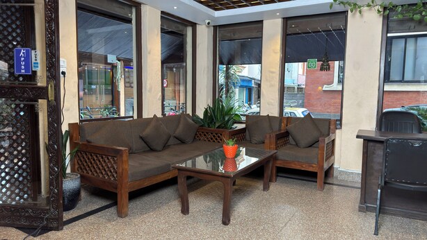 A seating area with a sofa and chairs, a glass table, and a potted plant. - Mala Suites Thamel (Kathmandu)