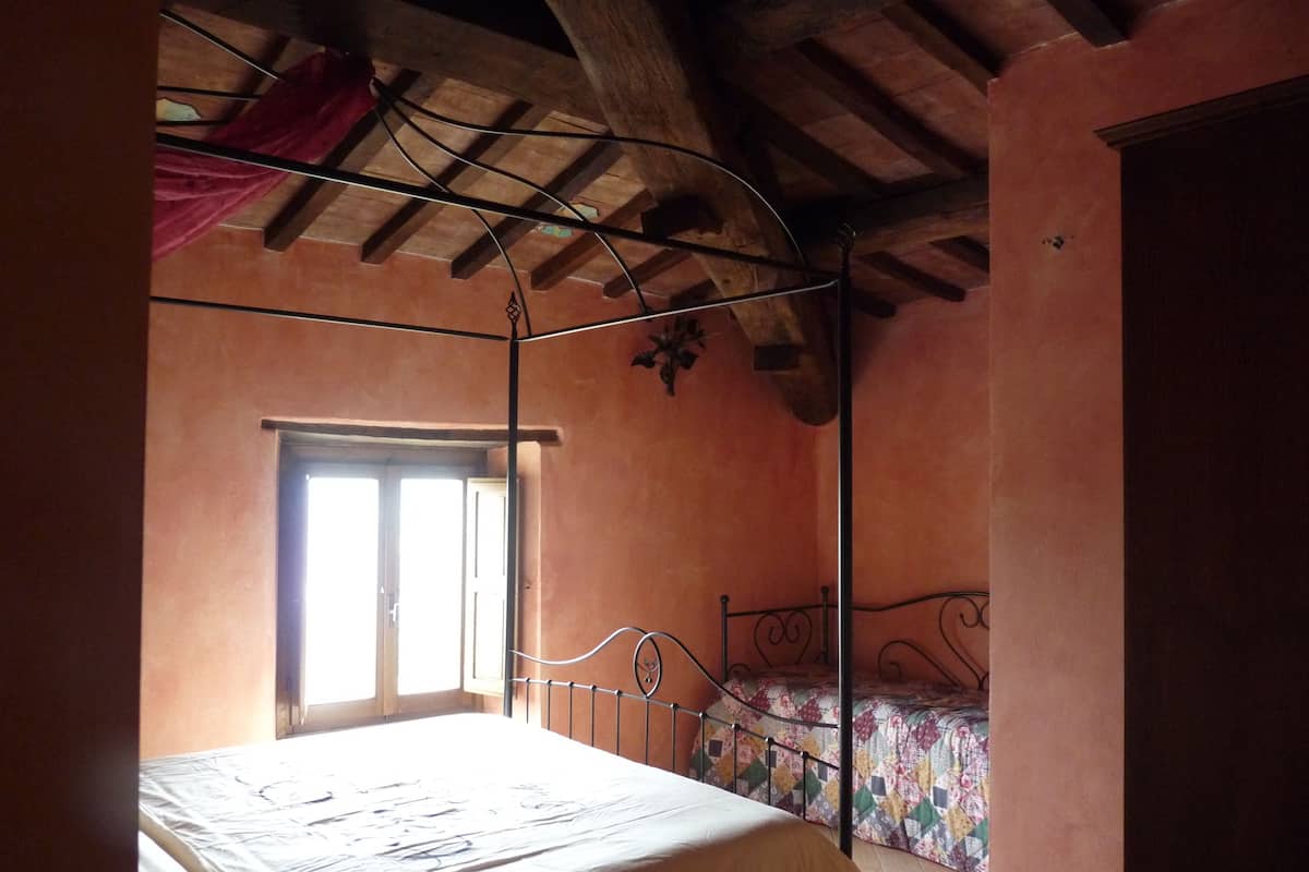 A bedroom with a single bed, a window, and a sloped ceiling.