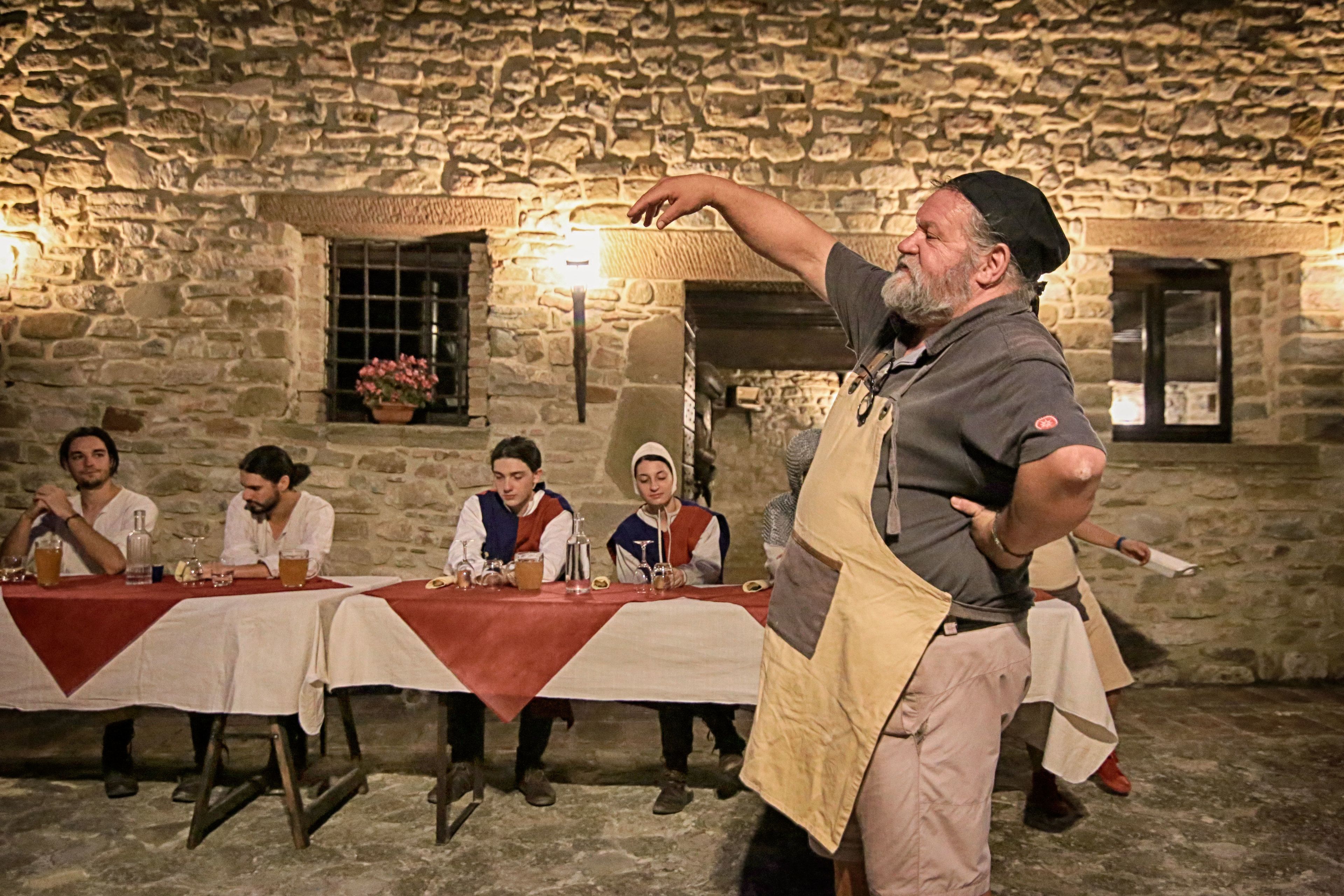 Une pièce aux murs de pierre, avec une longue table dressée pour un repas.
