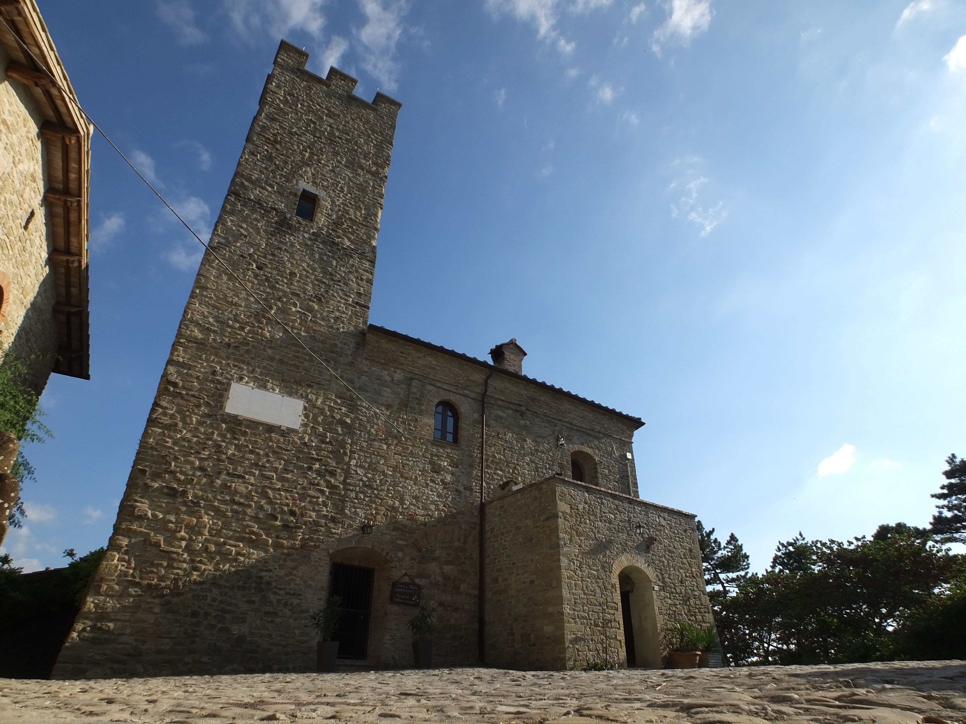 A historic stone building with a prominent tower and arched windows.