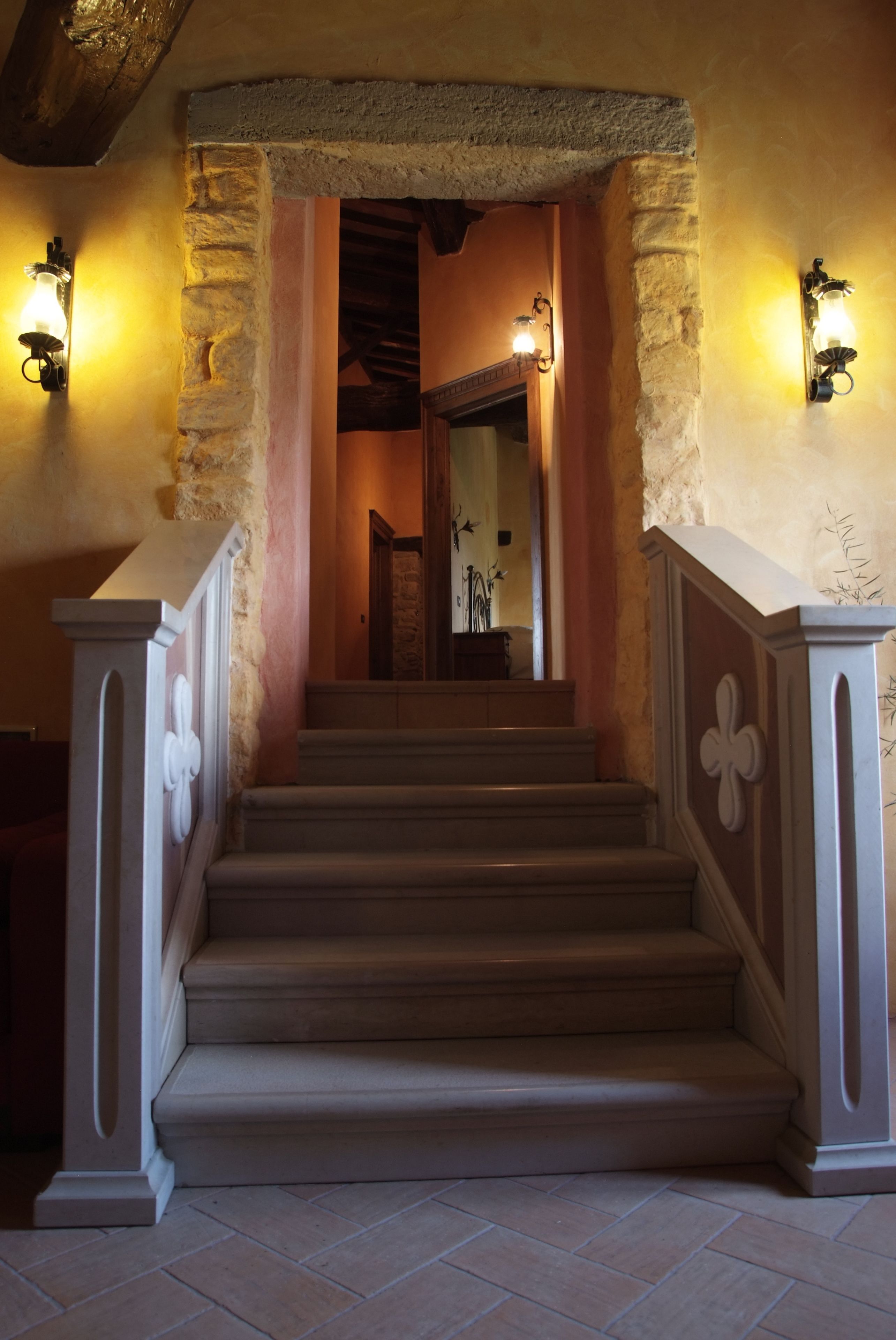 Una escalera con paredes de piedra y techo de madera que lleva a una habitación con chimenea.