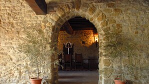 An arched stone doorway with potted plants on either side, leading to a room with a wooden ceiling and a chandelier. - Castello di Giomici (Valfabbrica)