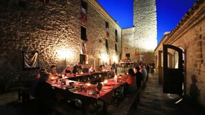 A stone-walled dining area with tables set for a meal, illuminated by candlelight. - Castello di Giomici (Valfabbrica)