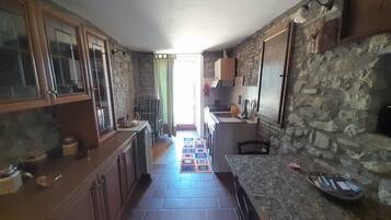 A kitchen with stone walls, wooden cabinets, and a tiled floor.