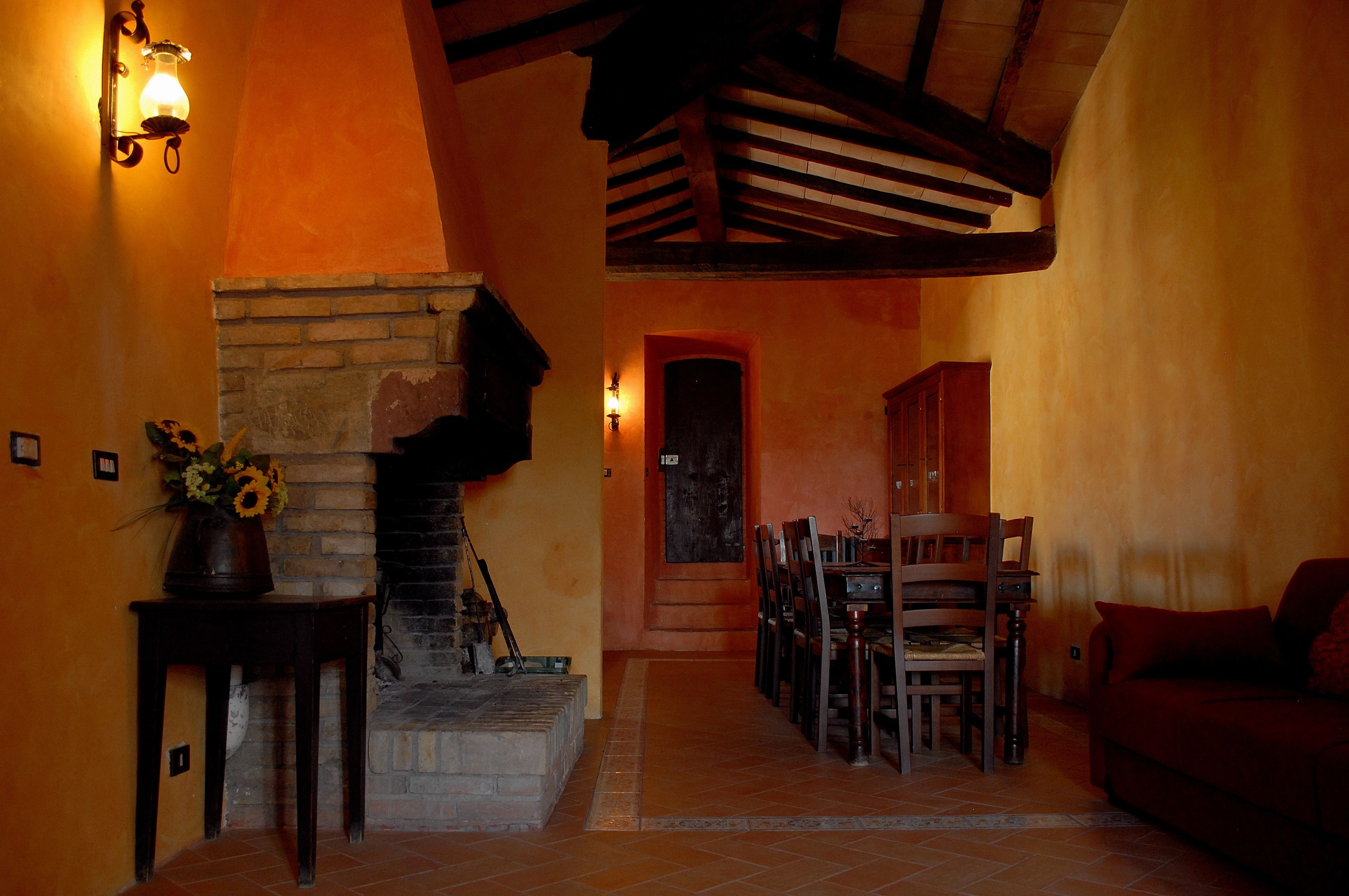 Um interior acolhedor com lareira, móveis de madeira e uma escada que leva a outro cômodo.