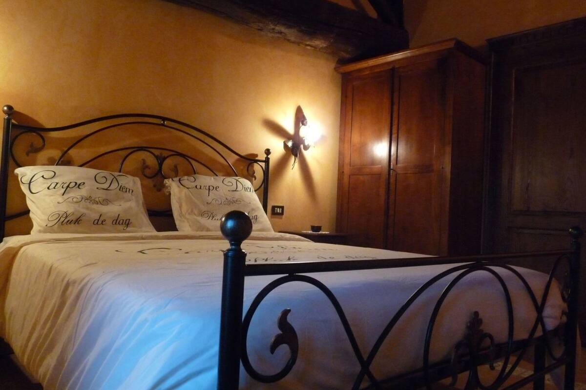 A bed with a metal frame, two pillows with text, a wall-mounted light, and wooden furniture.