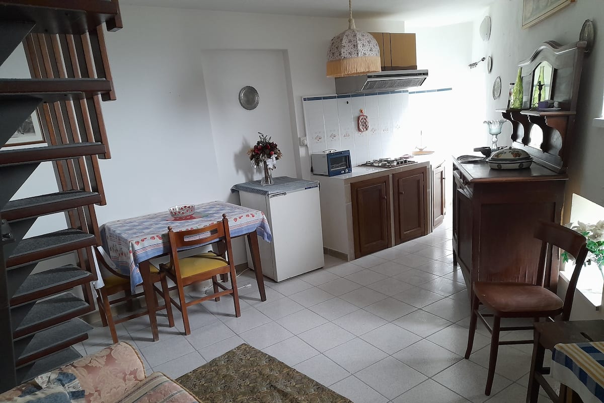 A compact kitchen with a dining area, a refrigerator, a microwave, and a small oven.
