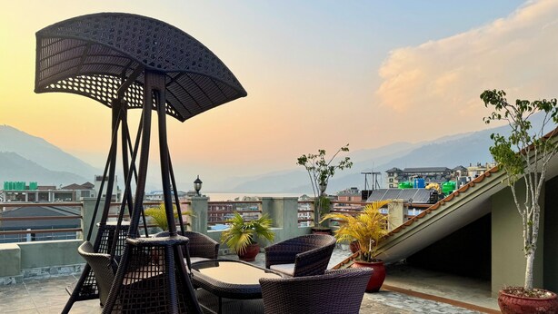A rooftop terrace with wicker furniture, a pergola, and potted plants. - Mount View Pokhara (Pokhara)