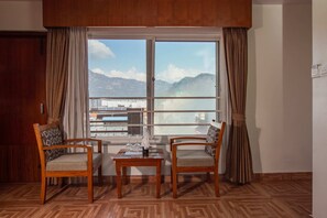 A room with two wooden chairs, a small table, and a large window with curtains. - Mount View Pokhara (Pokhara)