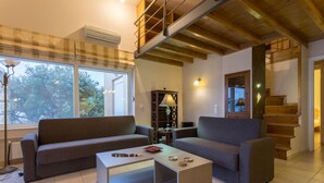 Ein modernes Wohnzimmer mit Sofa, Couchtisch und einer Treppe, die in einen oberen Bereich führt.