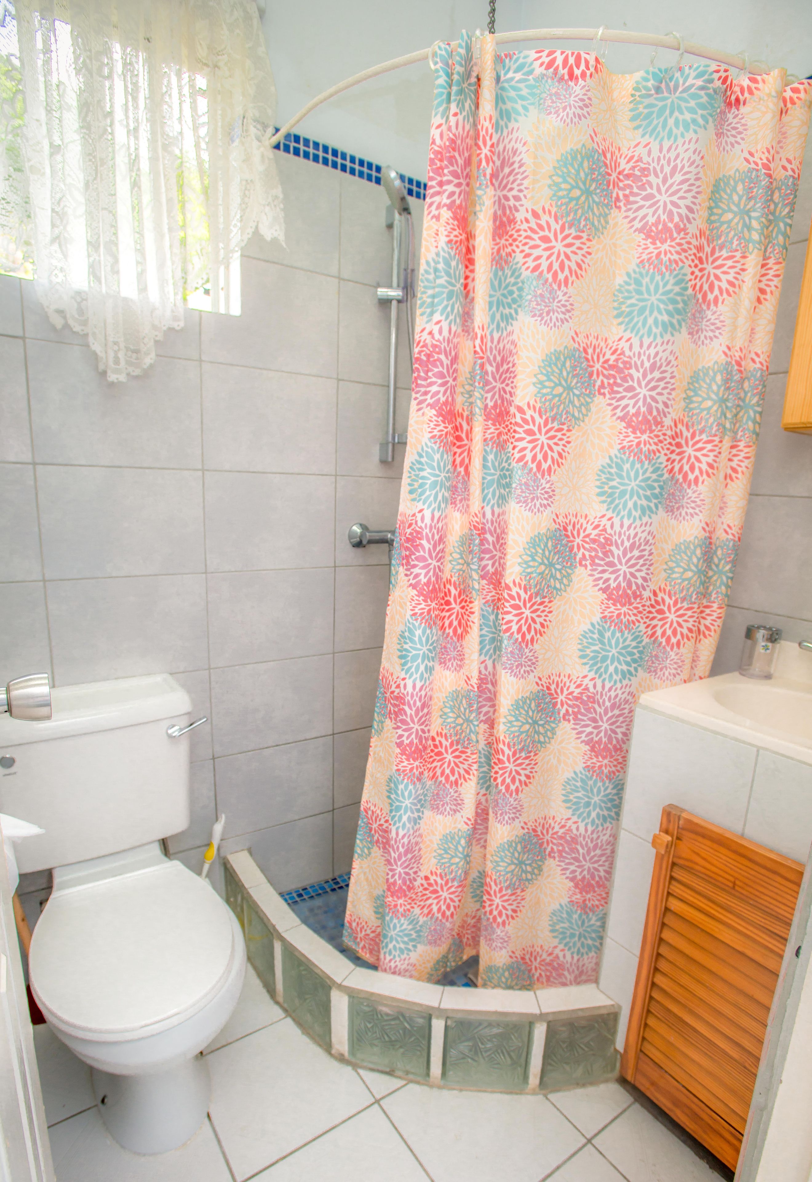 A bathroom with a shower curtain, toilet, and sink.