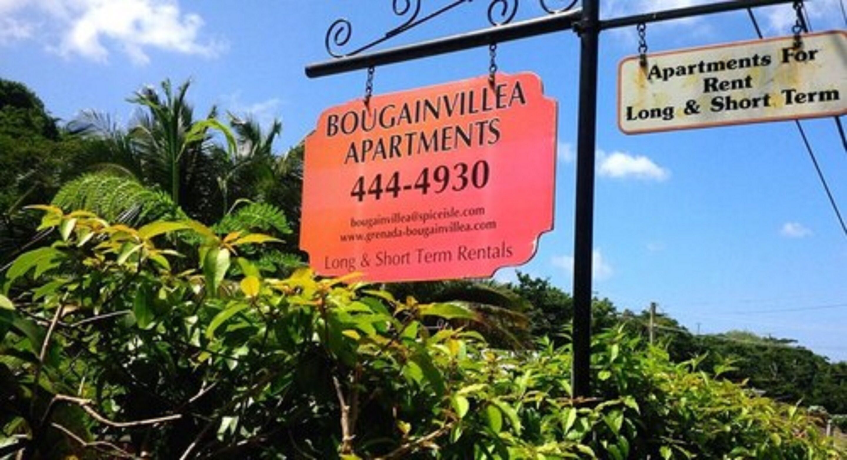 A sign for Bougainvillea Apartments advertising long and short term rentals.