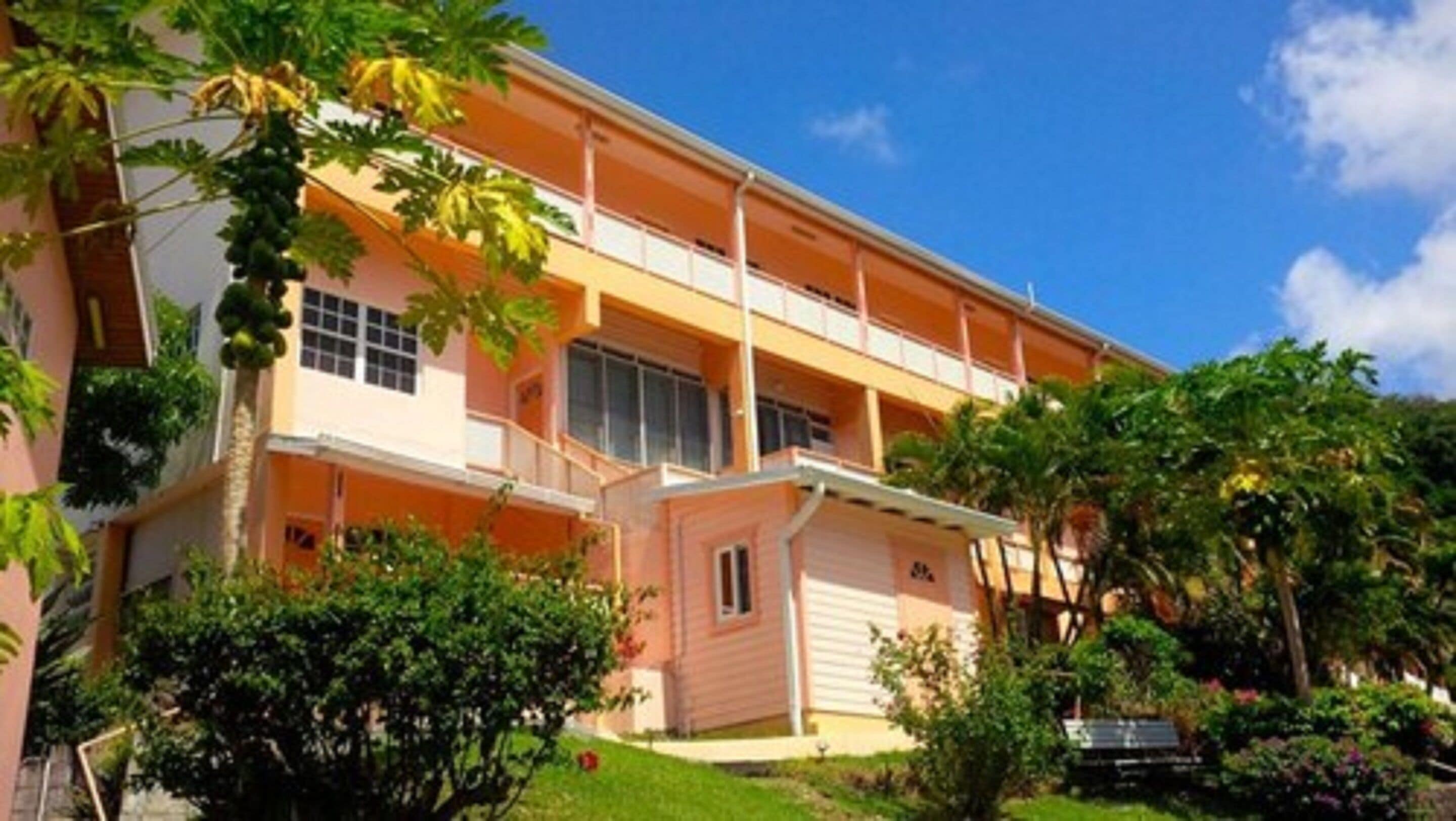 Un hotel de varios pisos con un patio central, balcones y abundante vegetación.
