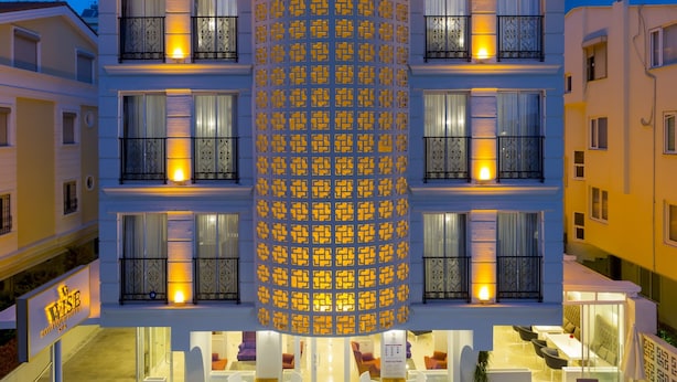 A hotel with a central cylindrical structure, multiple balconies, and a pool area with sun loungers. - Wise Hotel Spa & Adult Only (Antalya)