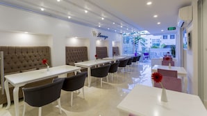 A modern lounge area with white tables and dark chairs, featuring a 'W Lounge' sign. - Wise Hotel Spa & Adult Only (Antalya)