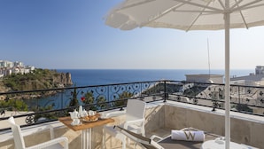 A balcony with a table set for two, overlooking a coastal view with buildings and cliffs. - Wise Hotel Spa & Adult Only (Antalya)
