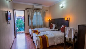 A hotel room with two beds, a TV, a balcony with curtains, and a view of the outdoors. - Kathmandu Sunny Hotel (Kathmandu)