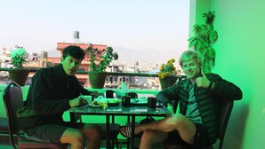 Two people sitting at a table with a city view in the background. - Kathmandu Sunny Hotel (Kathmandu)