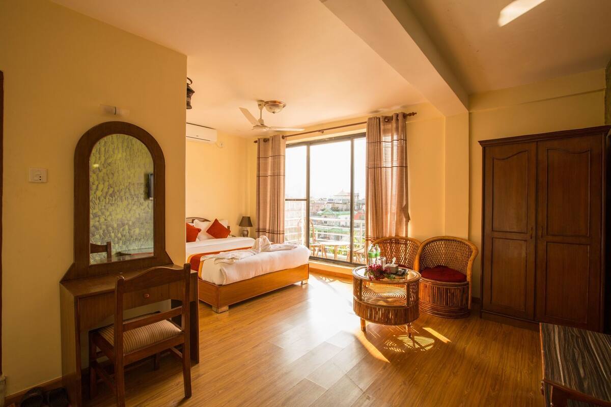 Una habitación de hotel con una cama, una silla, una mesa con un jarrón y un armario.