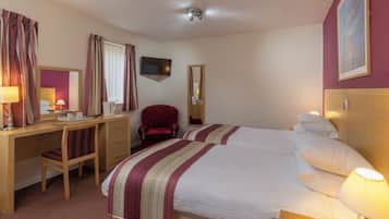 A hotel room with a bed, desk, chair, TV, and a mirror.