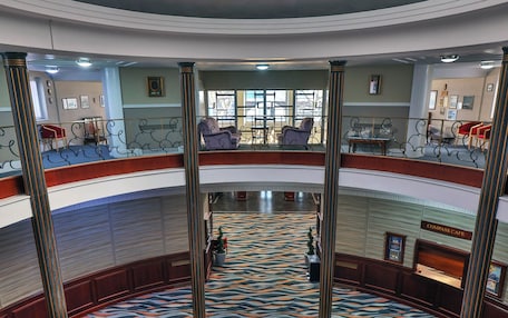 A multi-level atrium with a central circular seating area, a patterned floor, and a ceiling with circular light fixtures.