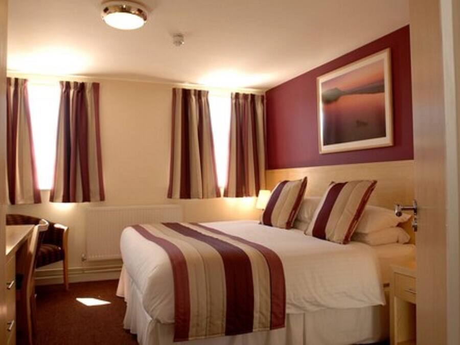 Een hotelkamer met een bed, een bureau en een stoel.