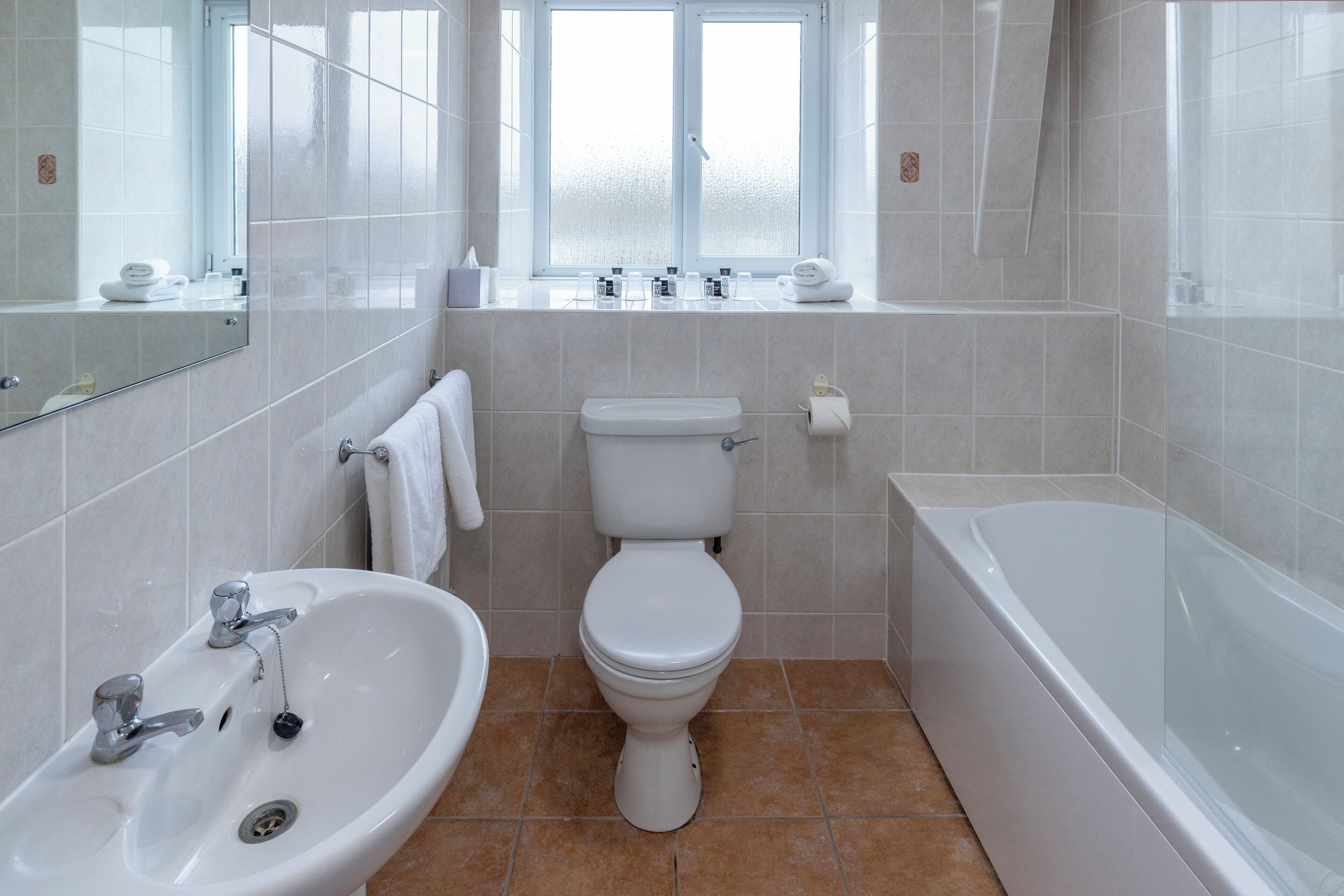 A bathroom with a sink, toilet, bathtub, and a window.