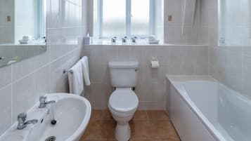 A bathroom with a sink, toilet, bathtub, and a window.