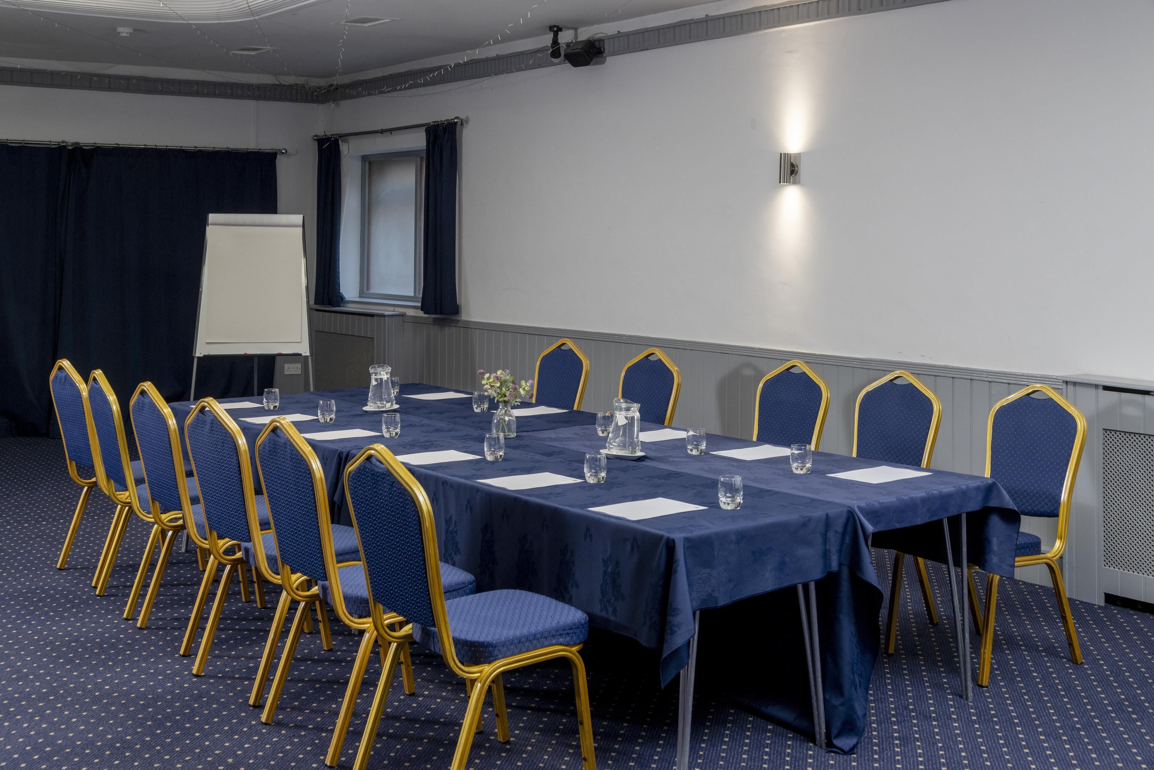 A conference room with a long table, blue chairs, and a whiteboard.