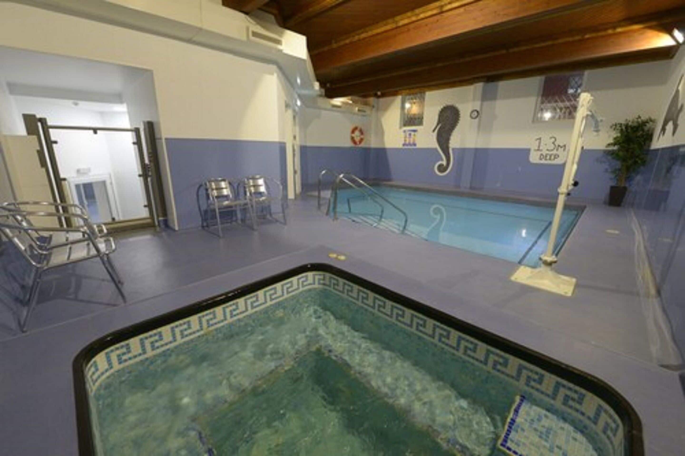 Piscina interior com trampolim, placa de salva-vidas e indicador de profundidade.