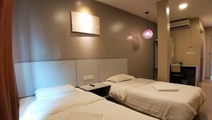 A hotel room with two beds, a bedside table, a wall-mounted light, and an air conditioning unit. - Hotel Jelai Temerloh (Temerloh)